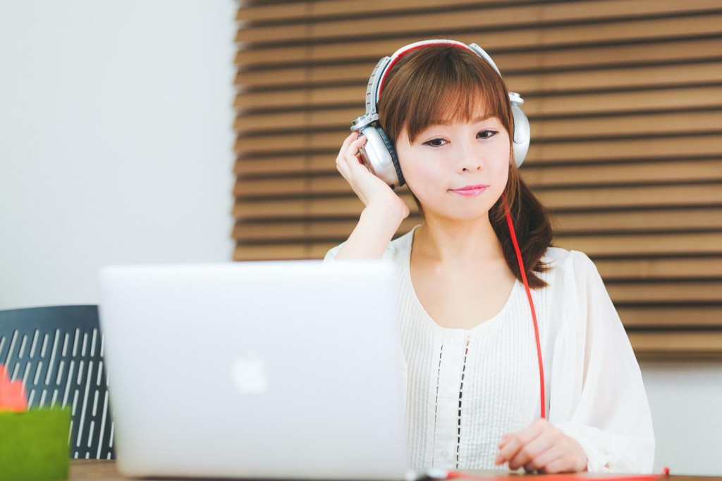 ヘッドフォンをして、パソコンで気楽に仕事をする女性