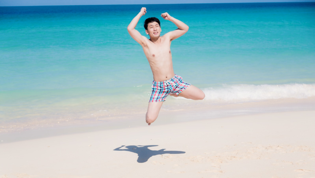 海辺で飛び跳ねる男性